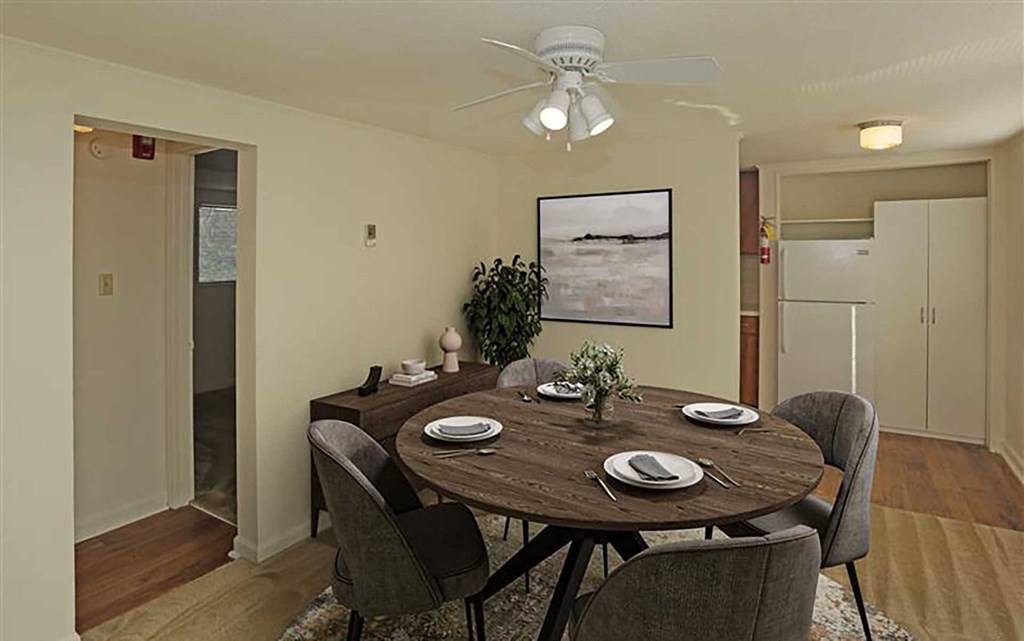 A dining room with a table set for two and a potted plant.