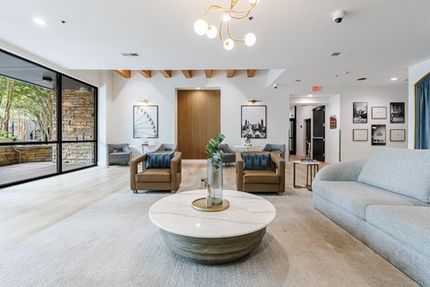 A living room with a large rug and a coffee table in the center.