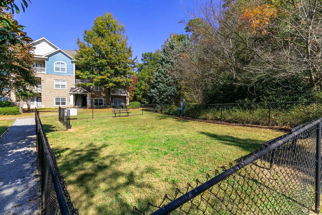 a yard with a fence and a house in the background