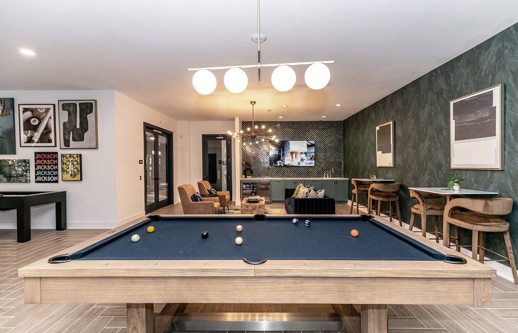 a pool table in a living room with a bar and a television