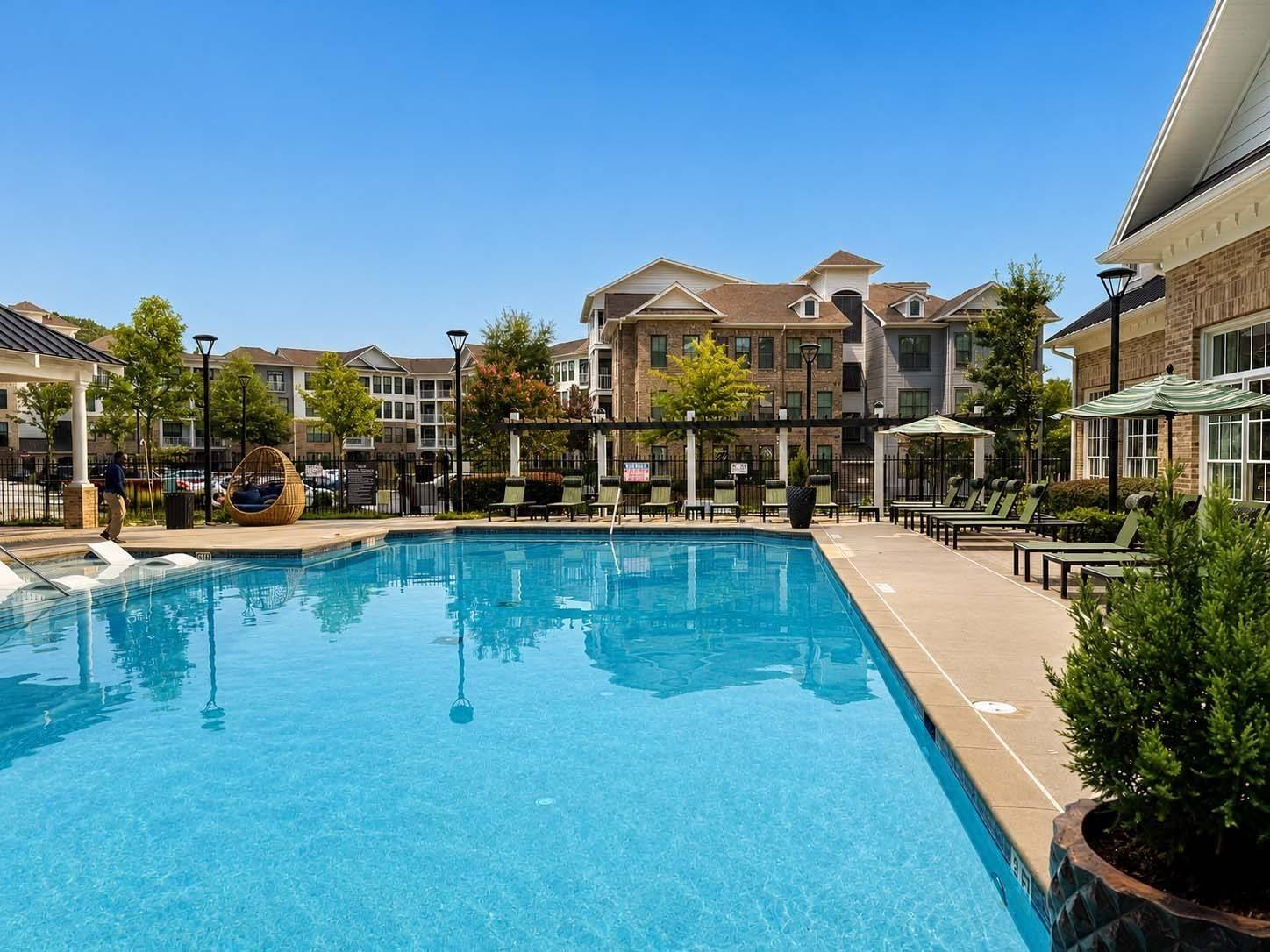A large swimming pool in front of a building with a clear blue sky.