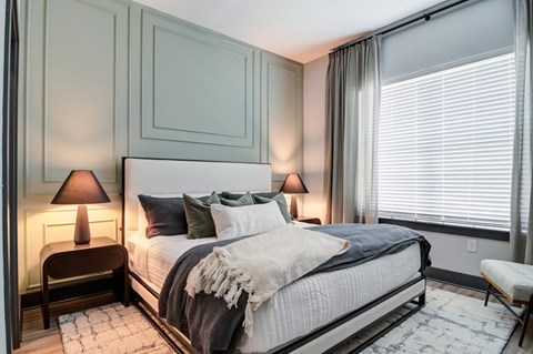 A bedroom with a large bed and two lamps.