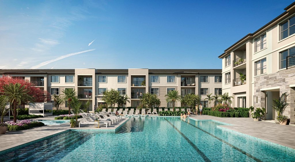 A large swimming pool is surrounded by lounge chairs in front of apartment buildings.