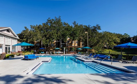 A large swimming pool surrounded by trees and lounge chairs.