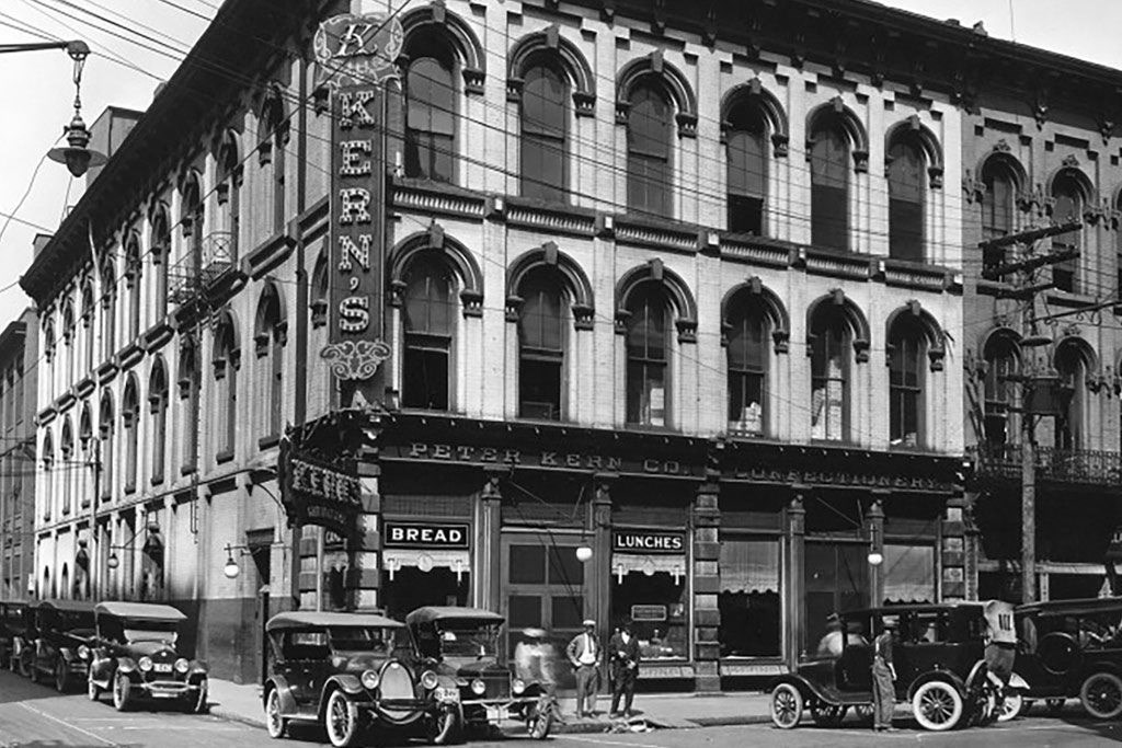 A black and white photo of a street with cars and a building with the word "Exeter's" on it.