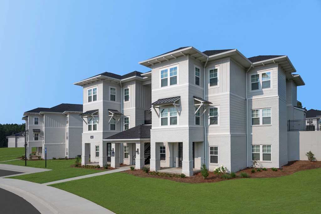 A row of modern houses with white exteriors and dark roofs.