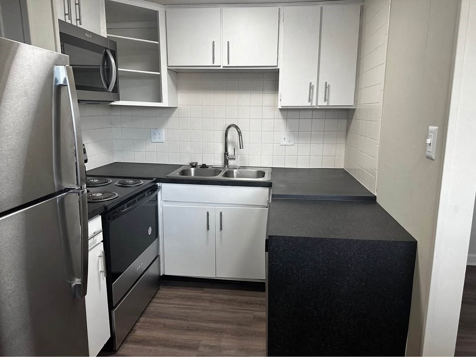 A kitchen with white cabinets and a black countertop.