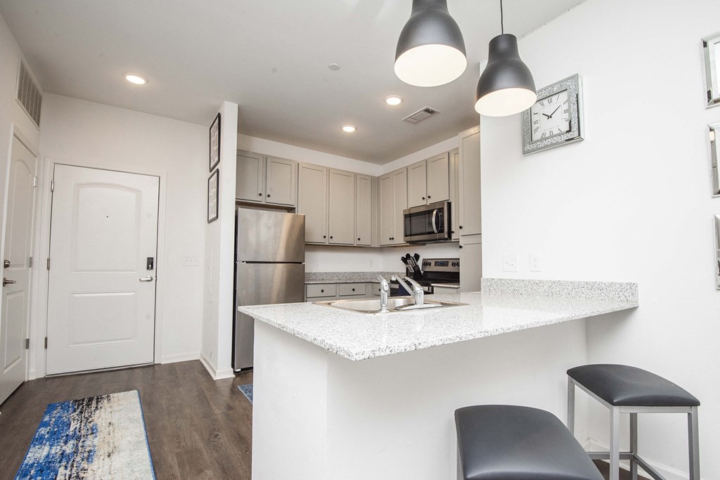 A kitchen with a white countertop and a blue rug on the floor.