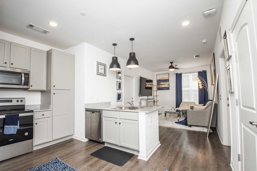 A modern kitchen with white cabinets and a wooden floor.
