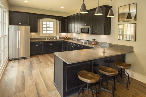 a kitchen with black cabinets and a large island with three stools