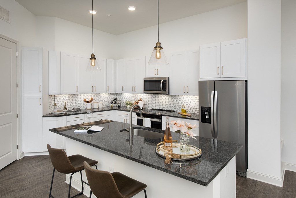 a kitchen with a large island and a stainless steel refrigerator