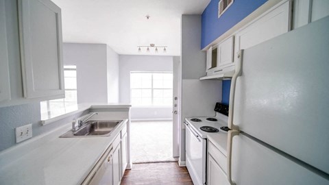 a kitchen with white cabinets and a sink and a refrigerator