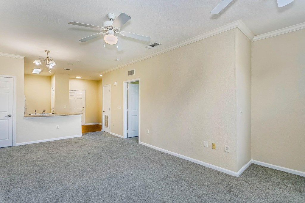 an empty living room with a ceiling fan
