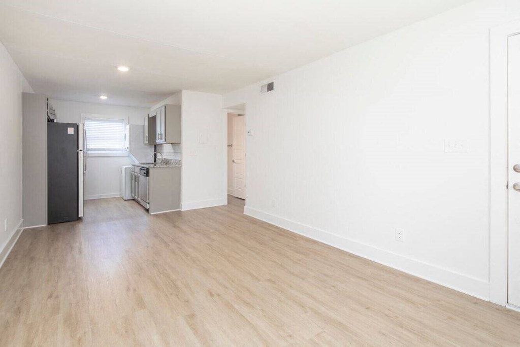 an empty living room and kitchen with a wood floor