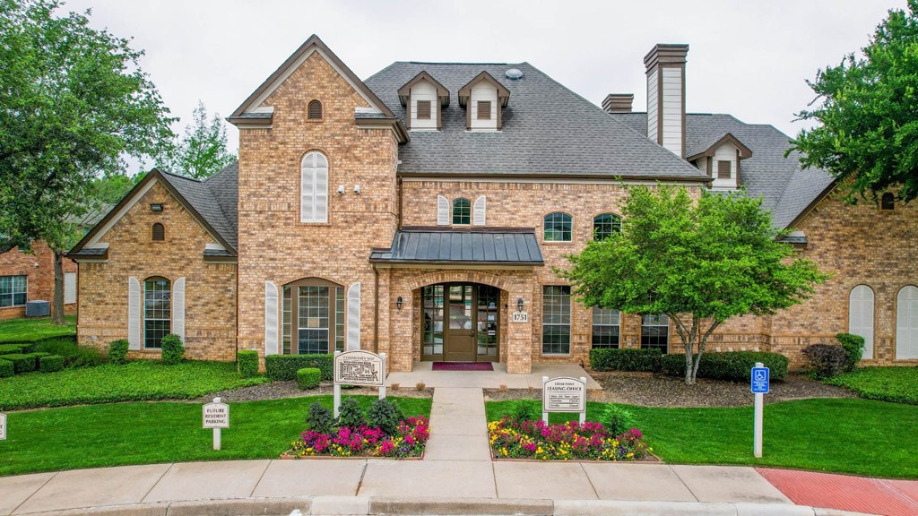 the front of a brick house with a driveway and landscaping