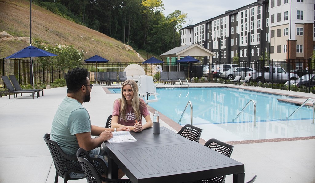 Two people sitting at a table by a pool.
