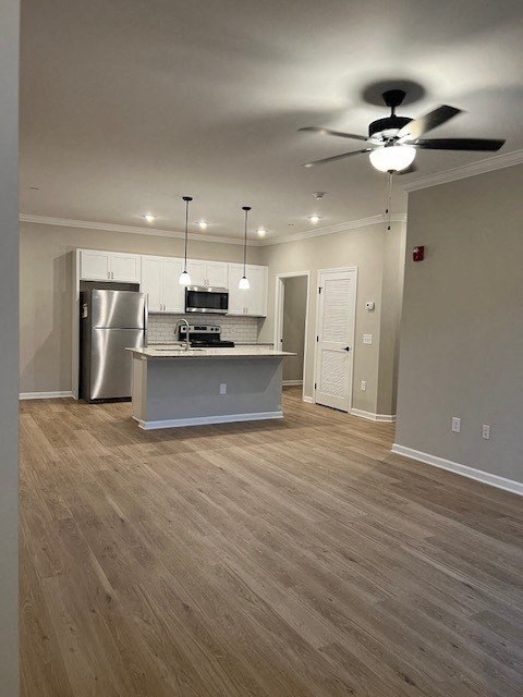 an empty living room with a kitchen and a ceiling fan