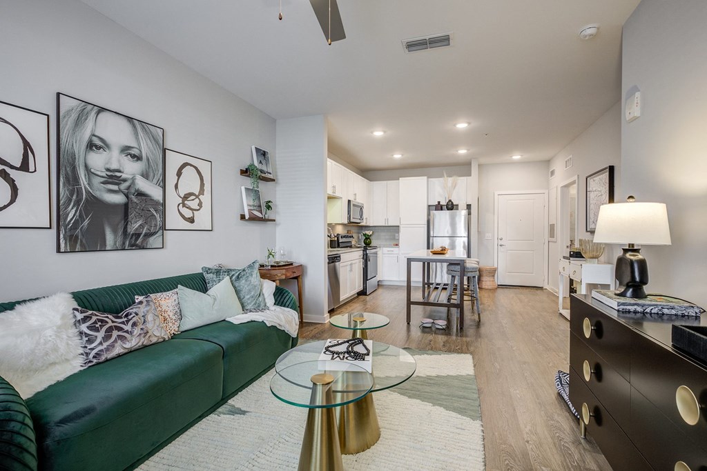 a living room with a green couch and a kitchen in the distance