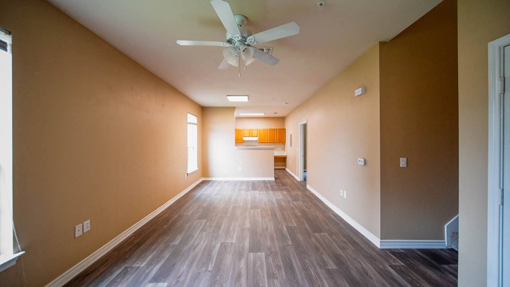 a empty living room with a ceiling fan and wood floors