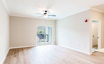 an empty living room with a ceiling fan and a balcony