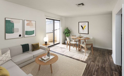 A living room with a white couch, a wooden coffee table, and a dining table with chairs.