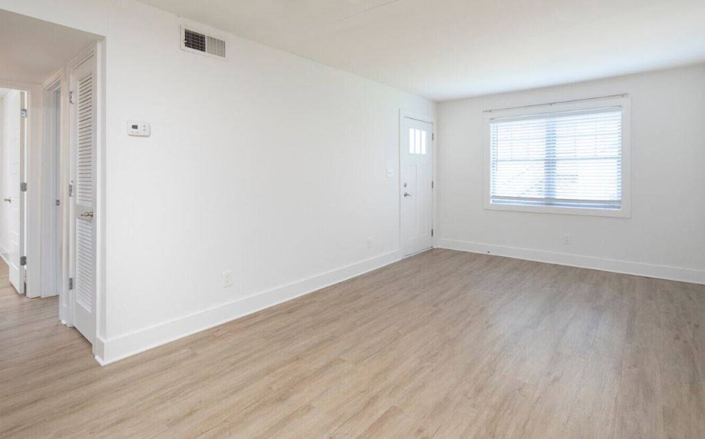 an empty living room with white walls and wood floors