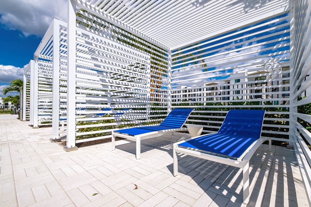 a patio with two blue lounge chairs and a white railing at Altis Blue Lake, Lake Worth, 33467