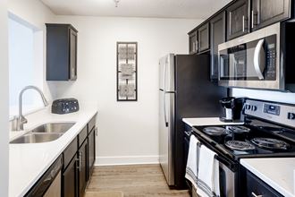 an apartment kitchen with black appliances and white counters and a stainless steel refrigerator