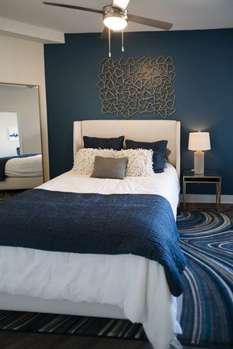 a blue and white bedroom with a white bed and a blue accent wall
