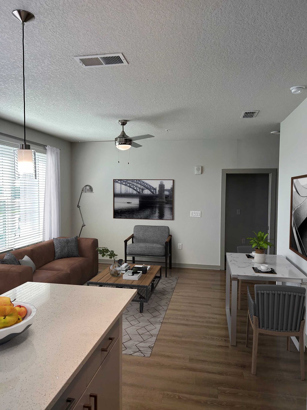 A living room with a brown couch, a coffee table, and a ceiling fan.