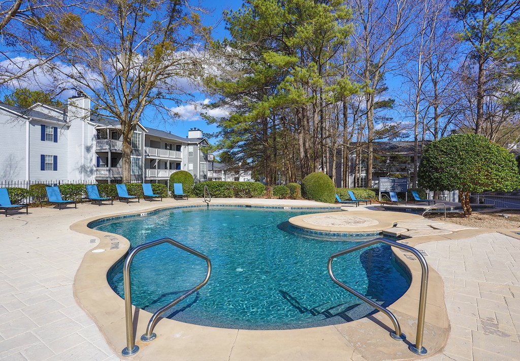a swimming pool with blue chairs and a building in the background