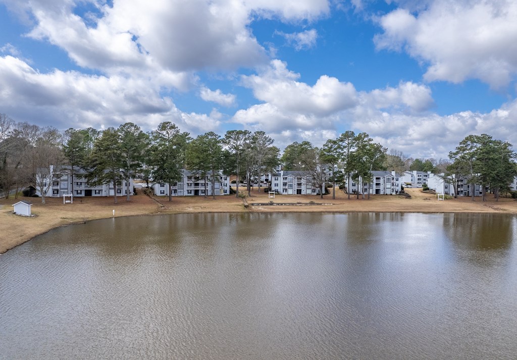 the view of a lake with apartments in the background and a cloudy sky