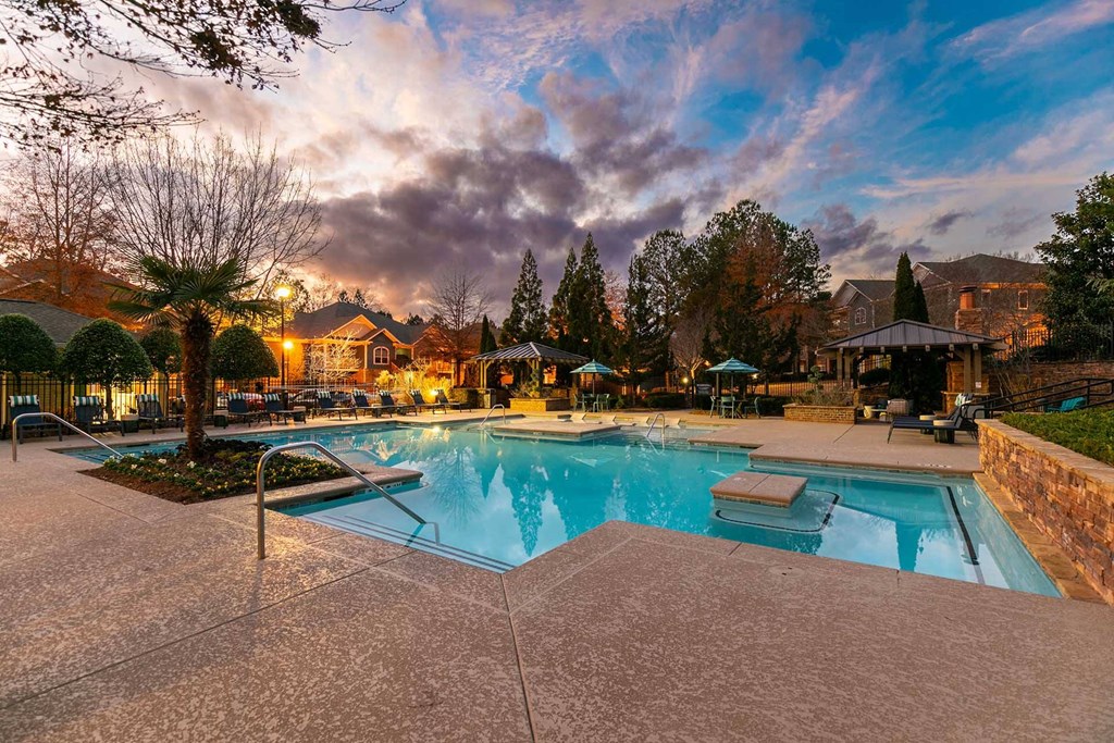 A swimming pool surrounded by a concrete patio and trees.