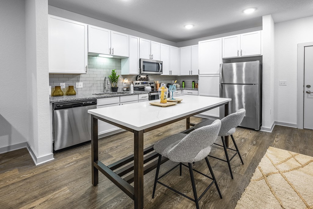 a kitchen with stainless steel appliances and a table with two chairs