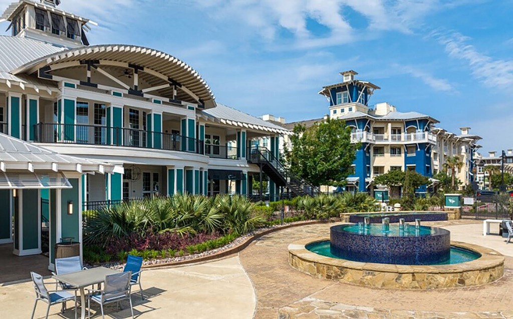 a fountain in front of a resort with tables and chairs