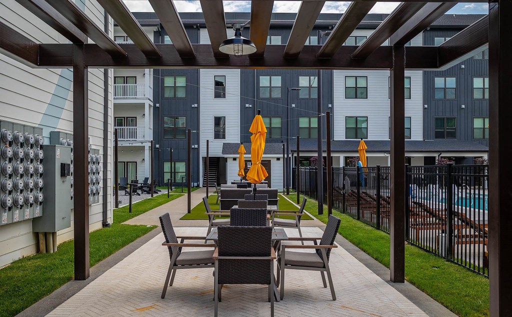 a patio with tables and chairs in front of an apartment building