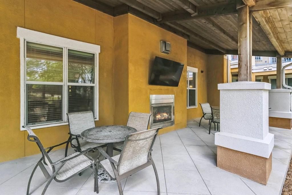a patio with a table and chairs and a fireplace