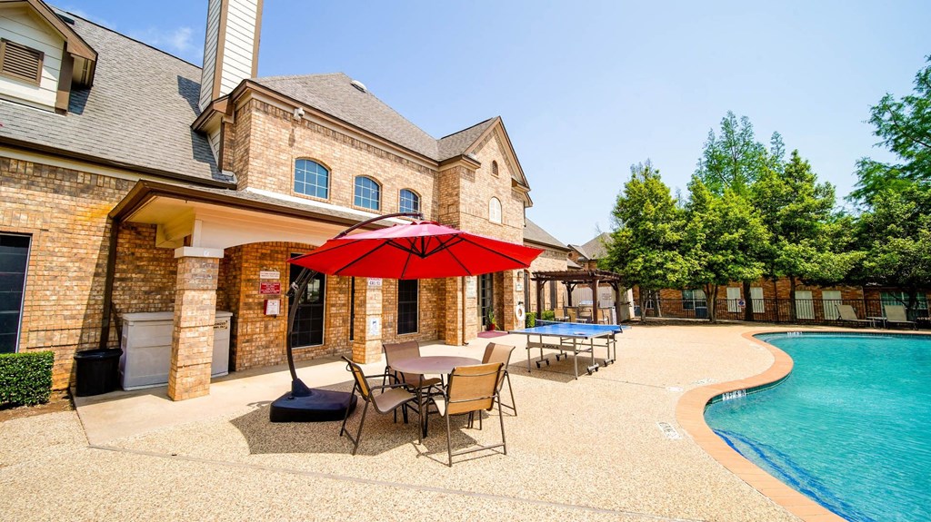 a backyard with a pool and a patio with tables and an umbrella