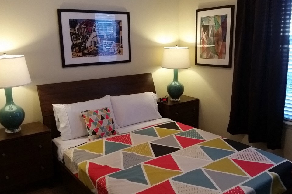 a bedroom with a bed with a colorful quilt