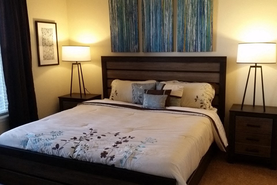 the master bedroom has a large bed and a large painting on the wall
