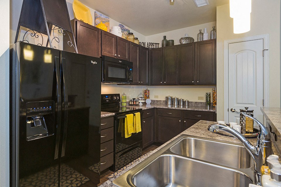 a kitchen with black cabinets and a stainless steel sink