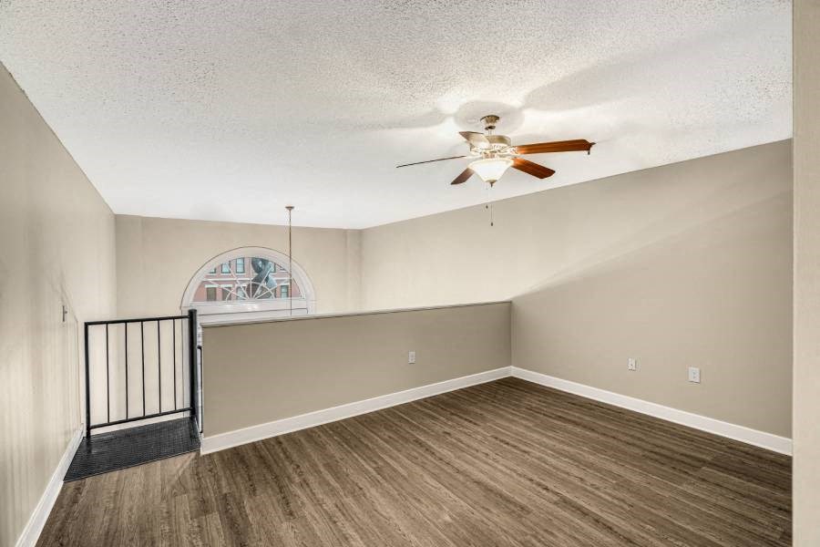 an empty living room with a ceiling fan and a staircase