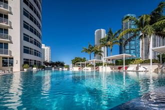 a swimming pool with palm trees in front of a tall building at Regatta at New River, Florida