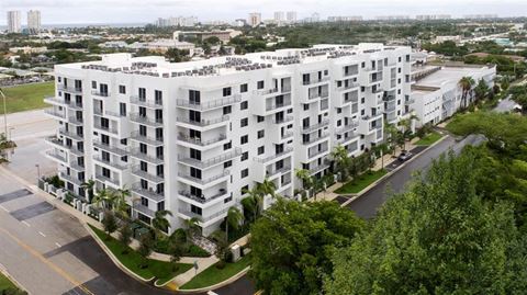 an aerial view of an apartment complex with trees in the foreground and a city in the background at Saba Pompano Beach, Florida, 33062