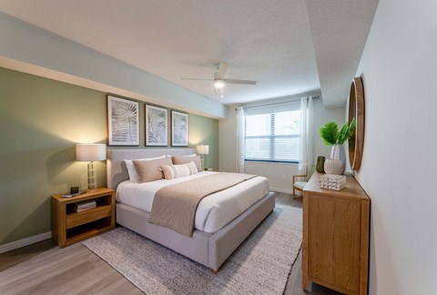 A bedroom with a large bed and a wooden nightstand.