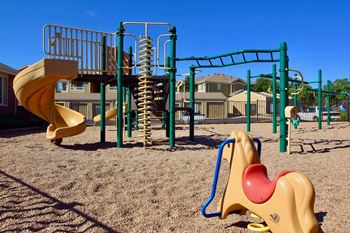 A playground with a yellow slide and a green monkey bar.