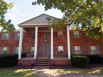 a red brick house with three white pillars in front of it - Photo Gallery