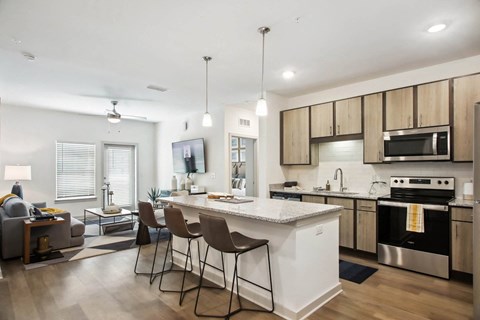 an open kitchen and living room with an island and chairs