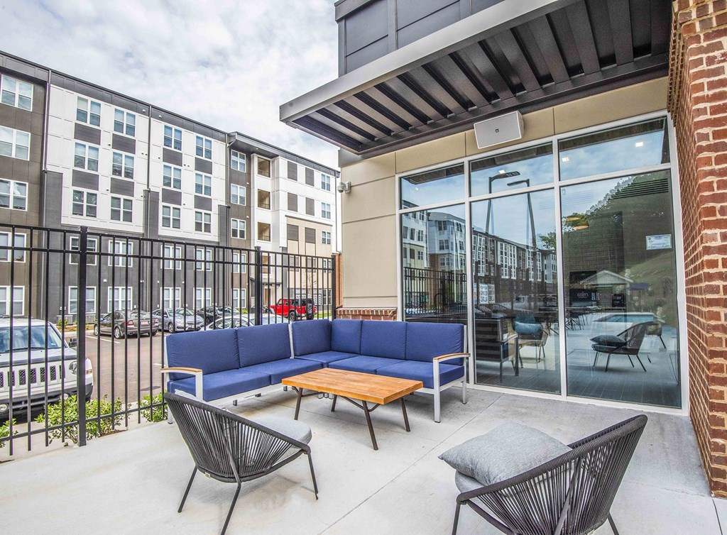 A patio with a blue couch and two chairs.
