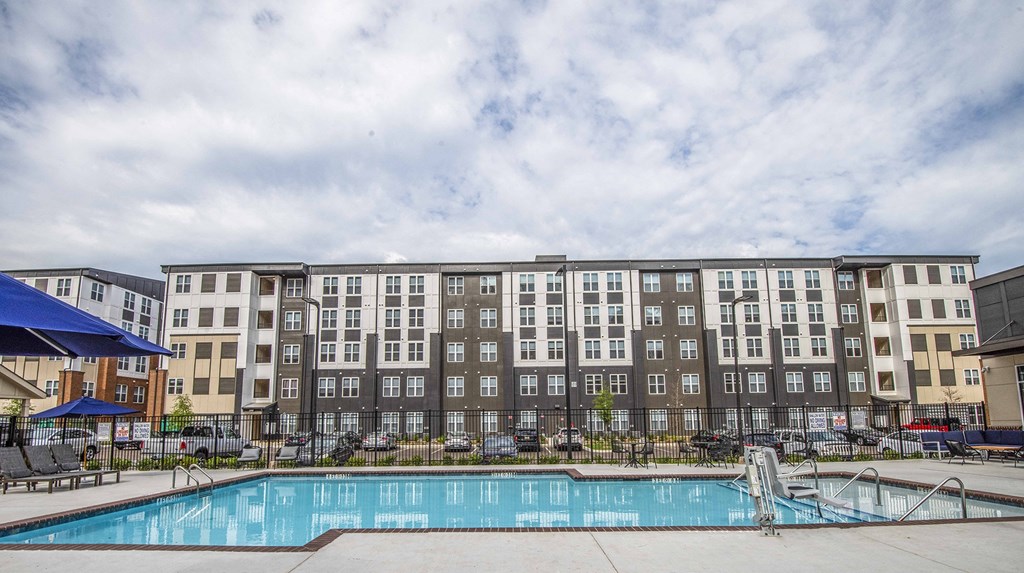 A large swimming pool in front of a multi-story apartment building.